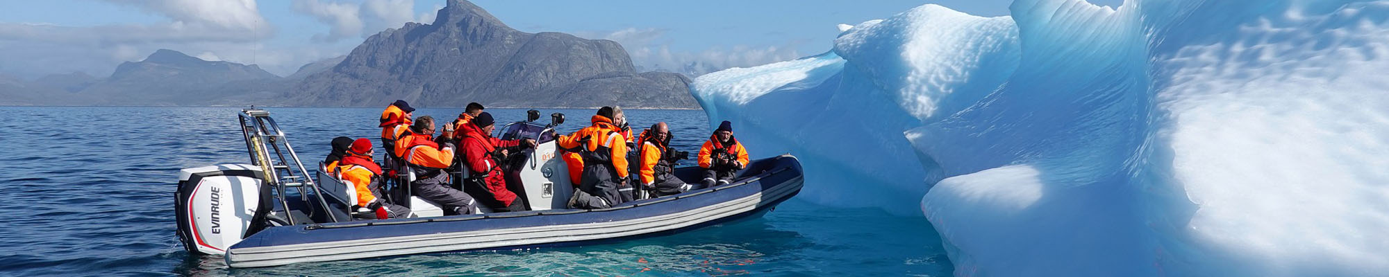 Greenland - people in boat looking at iceberg